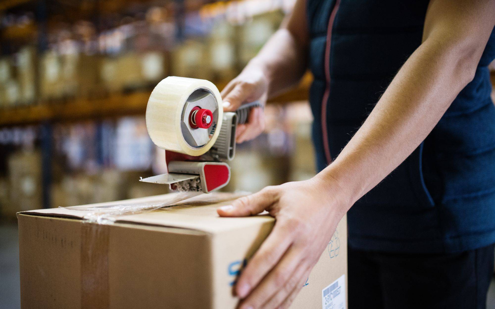Male Warehouse Worker Sealing Cardboard Boxes